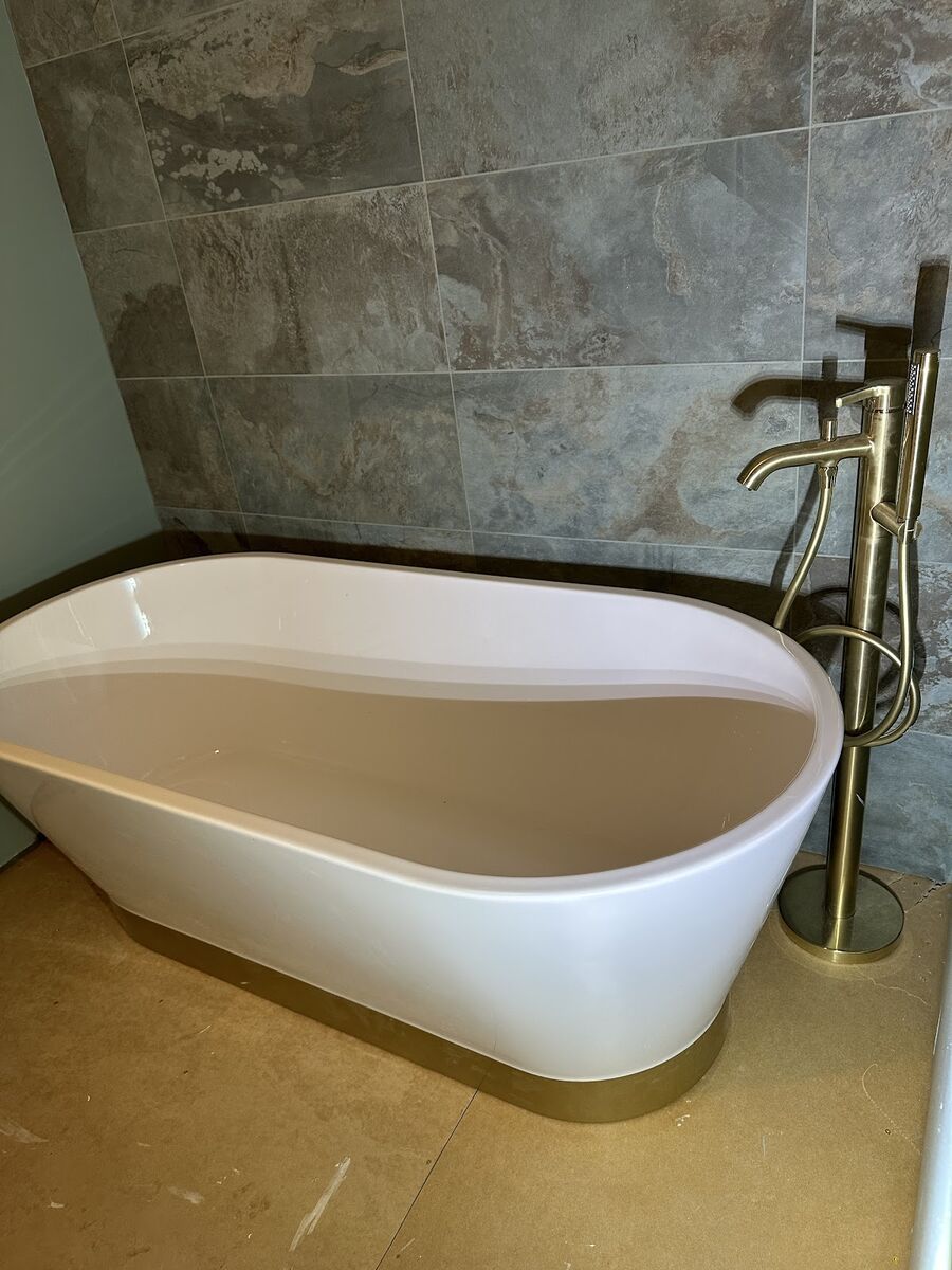 Contemporary freestanding bath with brushed gold floor-standing tap and marble-effect wall tiles